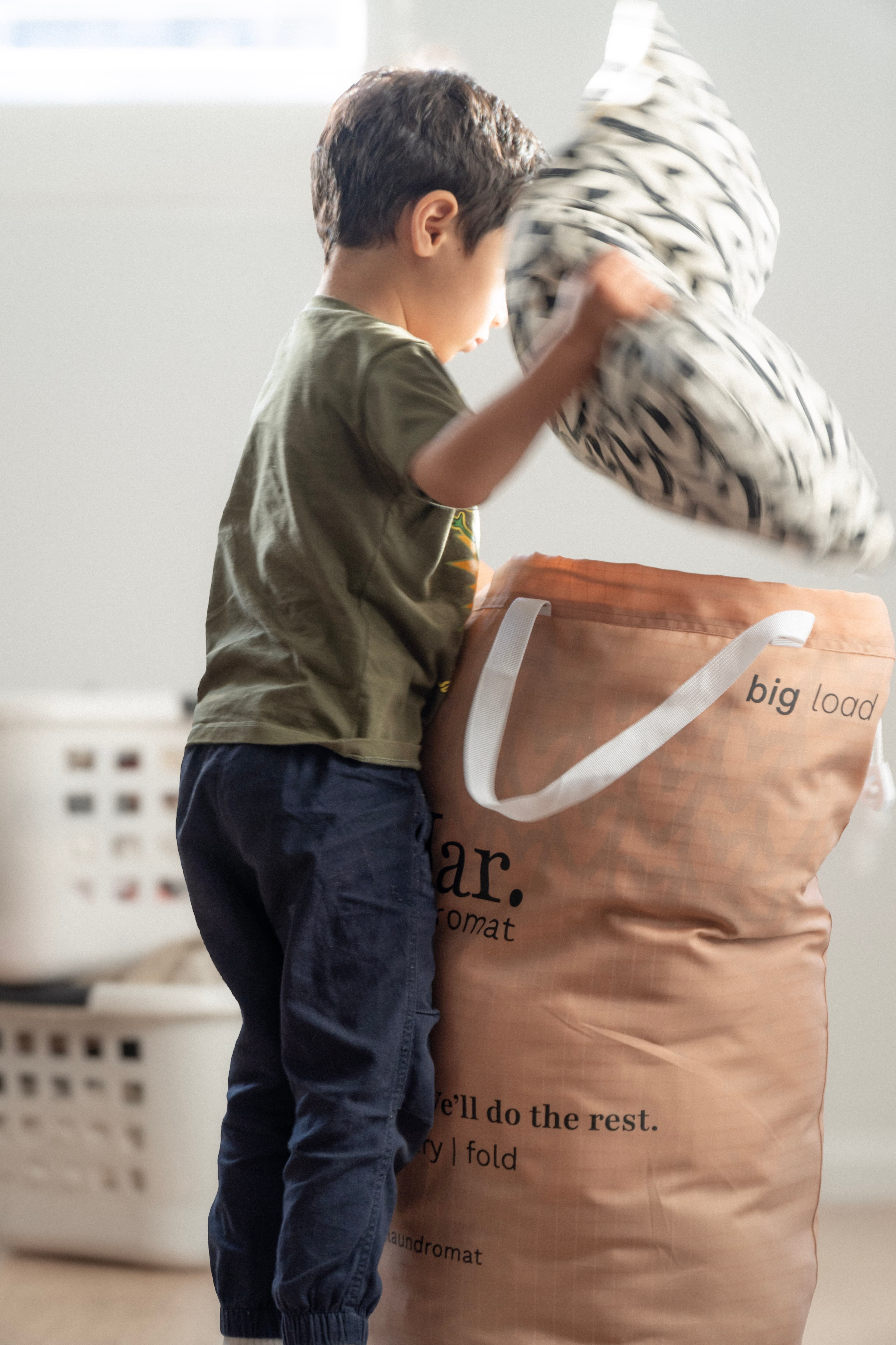 Child placing laundry into Mar. bag